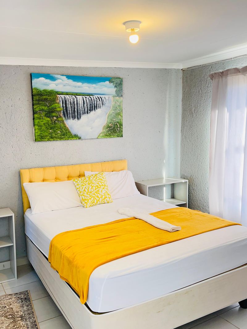 Room with golden tufted headboard and Victoria Falls painting